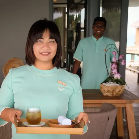 Resort staff offering refreshments in a tropical hospitality setting.