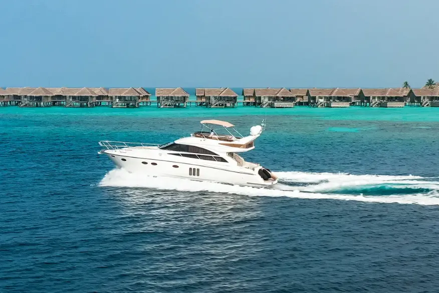 Private yacht cruising through the lagoon at Vakkaru Maldives with overwater villas and tropical island views.