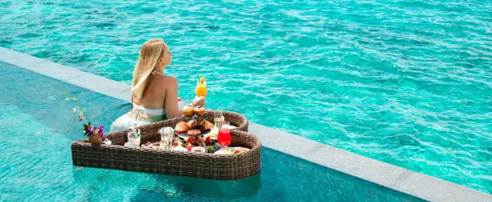 A lady in a private overwater infinity pool at Vakkaru Maldives enjoying a floating breakfast