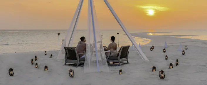 Couple celebrating with champagne during a romantic beach dinner at Vakkaru Maldives by the ocean