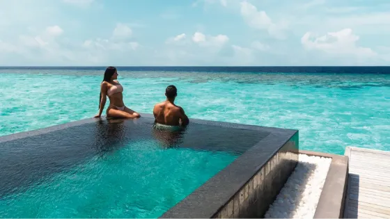 Couple in overwater infinity pool overlooking the turquoise ocean at Vakkaru Maldives