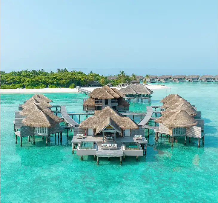 Overwater bungalows at Vakkaru Maldives connected by wooden walkways above a turquoise lagoon.