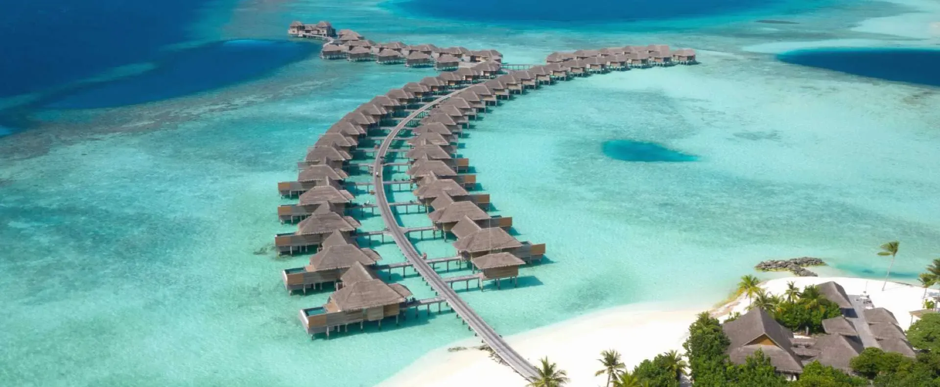Curved overwater villas at Vakkaru Maldives extending gracefully across the turquoise lagoon.