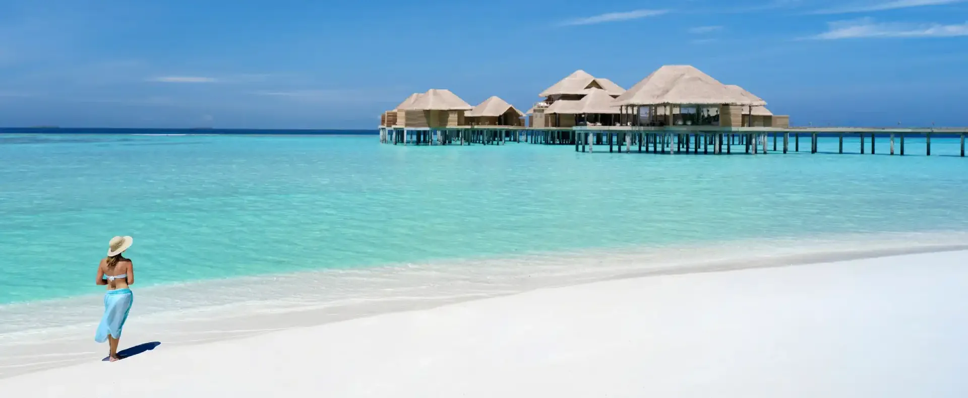 Guest enjoying ocean views from the beach at Vakkaru Maldives overlooking overwater villas and lagoon waters.