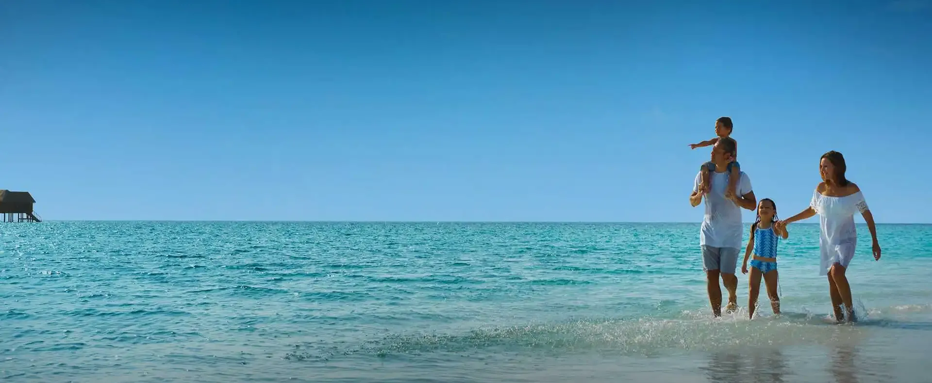 Family walking along the beach and enjoying the turquoise waters of the Maldives