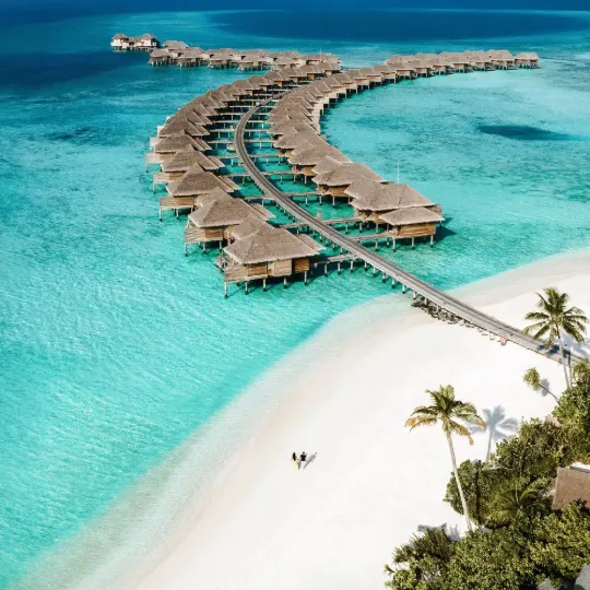 Aerial view of Vakkaru Maldives with overwater villas over a turquoise lagoon.