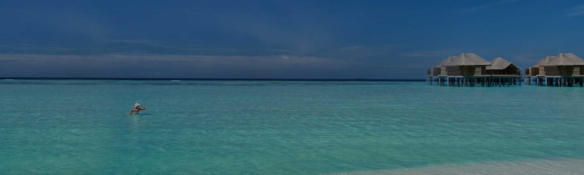 A girl swimming on the Maldives beach near the villas