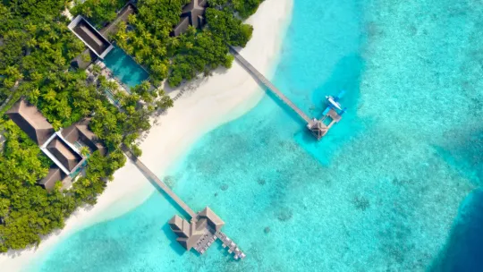 Aerial view of Vakkaru Maldives Residence showcasing a luxury island resort surrounded by turquoise waters and coral reef in Baa Atoll.