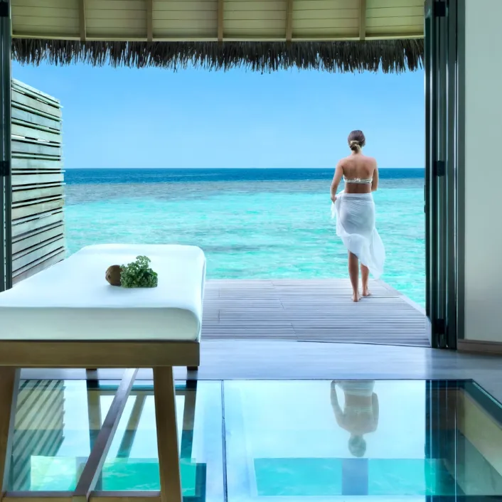 Spa treatment room at Vakkaru Maldives with glass floor overlooking lagoon.