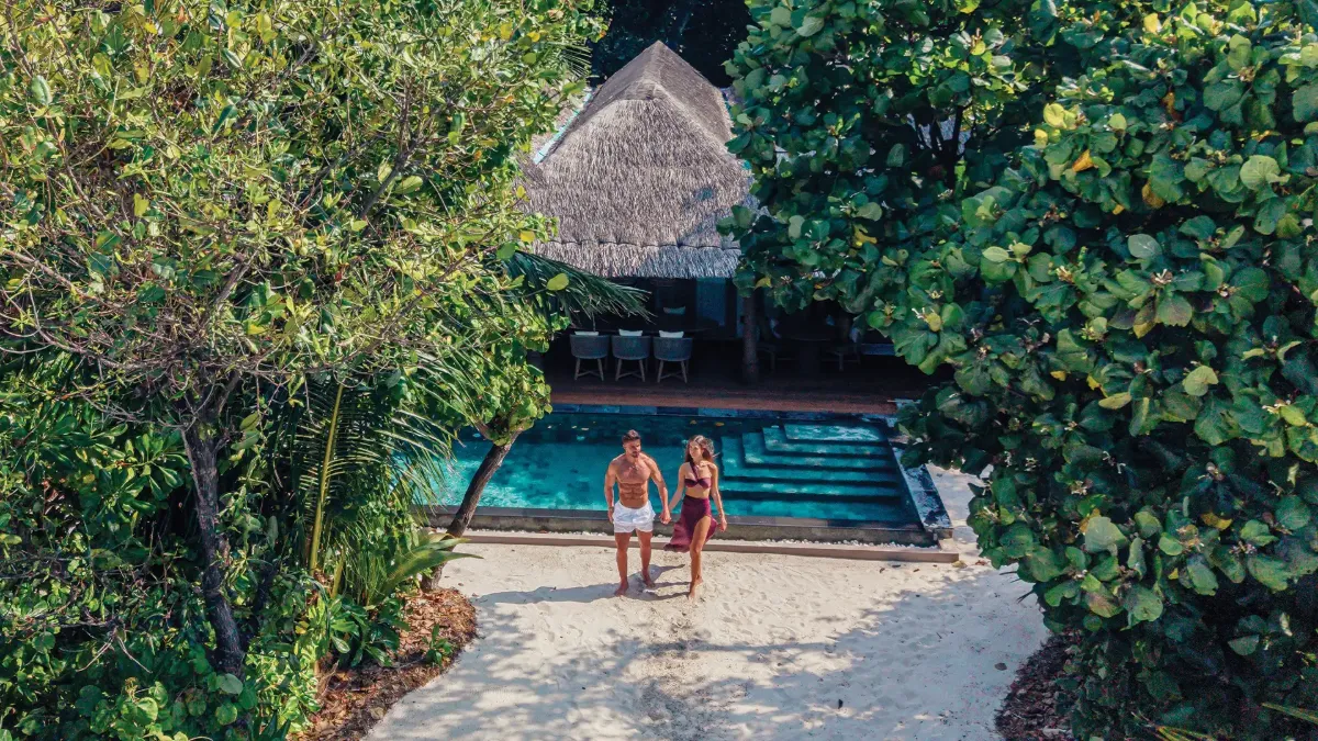 Romantic walk at Vakkaru Residence through lush tropical greenery near a villa and pool.