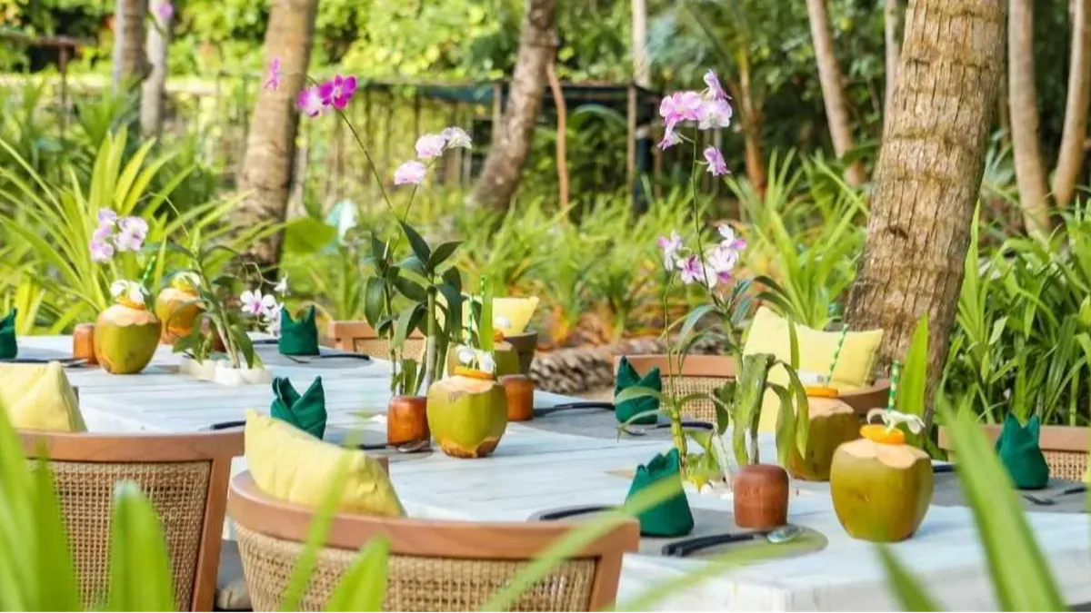 Garden dining setup at Vakkaru Maldives decorated with coconuts, orchids and tropical accents.