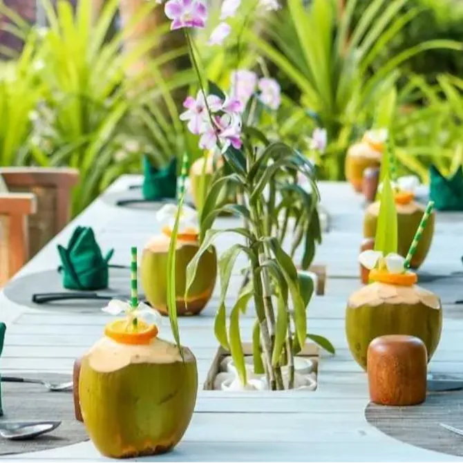 Garden dining setup at Vakkaru Maldives decorated with coconuts and orchids.