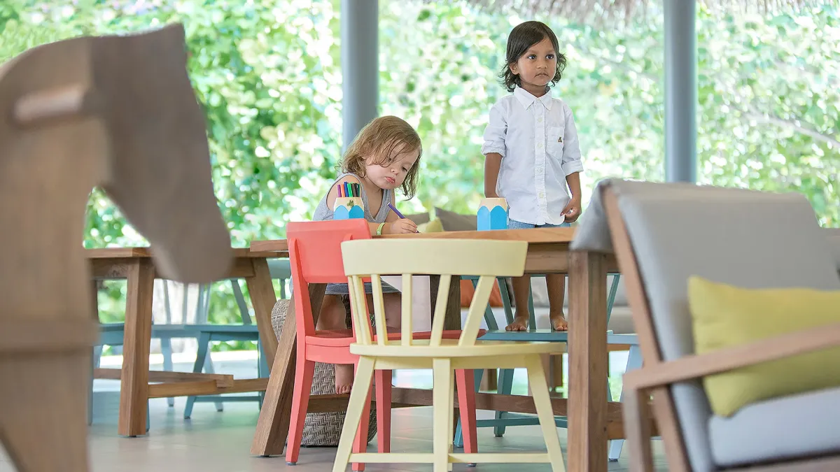 Children playing indoors at Vakkaru Residence with greenery visible outside.