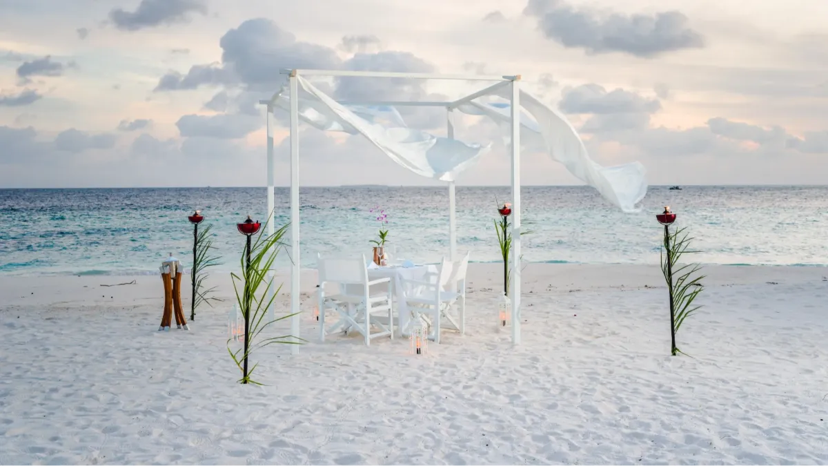 Romantic beach dining experience at Vakkaru Maldives beneath a private canopy beside the turquoise lagoon.
