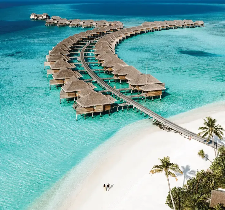 Aerial view of overwater villas extending into turquoise ocean and white sand beach at Vakkaru Maldives