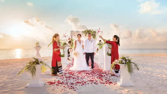 Couple celebrating a tropical beach wedding ceremony at sunset on the white sands of Vakkaru Maldives